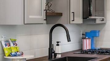 A kitchen with grey cabinets, a black faucet, and a microwave.