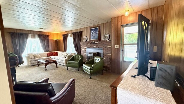 A cozy living room with a fireplace, a sofa, armchairs, and a television.