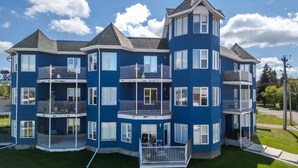 Un edificio residencial de varios pisos con balcones, un patio central y un césped bien cuidado.