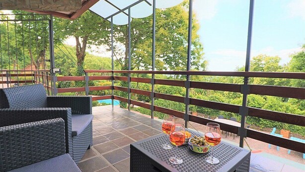 A covered outdoor seating area with wicker furniture, a table with drinks, and a view of greenery. - Villa Lisa: A characteristic and welcoming three-story villa in a quiet position, located on a hillside above the sea, with Free WI-FI. (Sorrento)