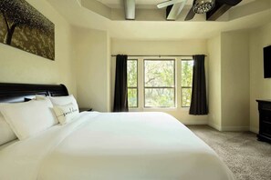 Un dormitorio con una cama grande, un ventilador de techo y una ventana con cortinas.