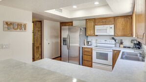 Une cuisine compacte dotée d’appareils électroménagers intégrés, de meubles en bois et d’un puits de lumière.