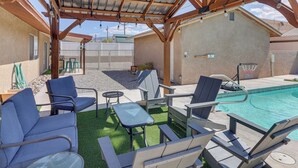 Une terrasse extérieure dotée d’une piscine, d’un espace salon et d’une partie abritée avec un toit en m étal.
