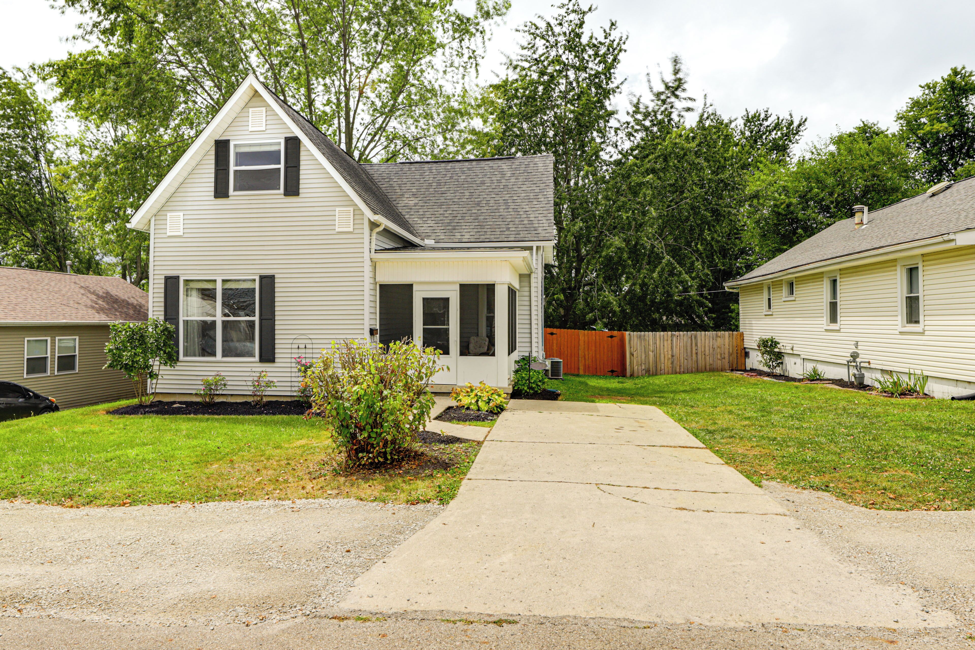 A two-story house with a front porch, a driveway, and a fenced backyard.