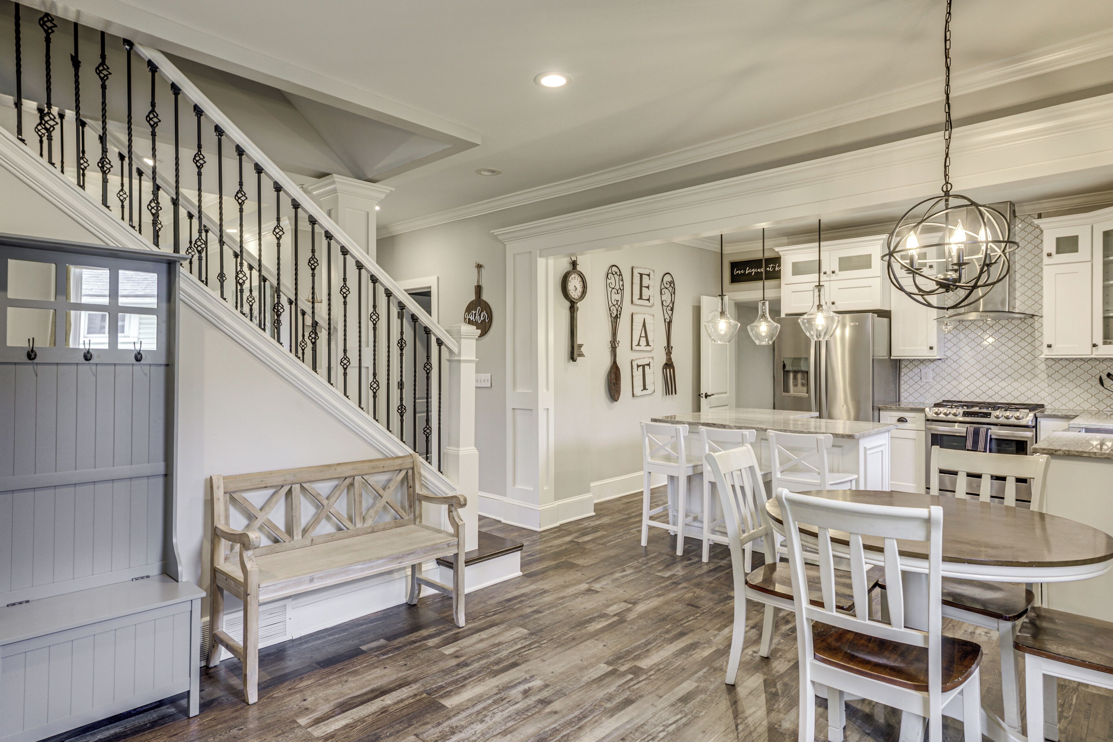 A spacious kitchen with a central island, white cabinetry, and a modern chandelier.