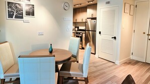 Una cocina moderna con armarios de madera, un refrigerador de acero inoxidable y un comedor con una mesa redonda y sillas.