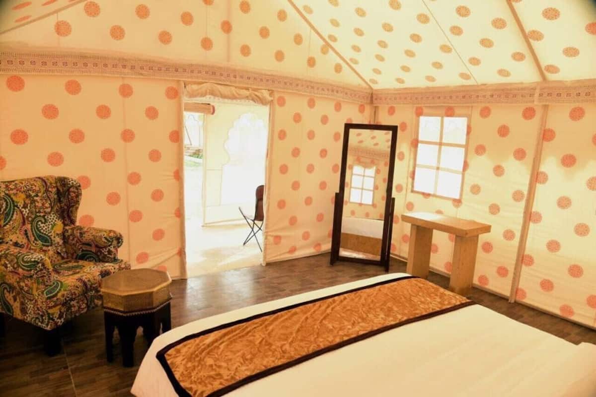Une pièce aménagée avec une tente, un lit, une chaise, une petite table et un miroir.