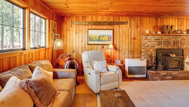 Un intérieur de chalet chaleureux avec une cheminée, des meubles en cuir et une grande fenêtre.