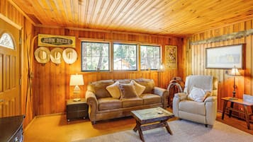 A cozy room with wooden walls and ceiling, a leather sofa, a wooden coffee table, and a chair.