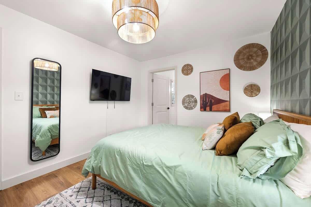 A bedroom with a bed, a television, and decorative wall art.