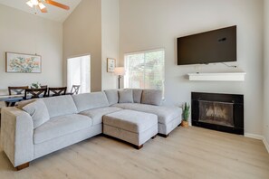 A living room with a sectional sofa, a flat-screen TV mounted above a fireplace, and a dining area with a table and chairs. - Easy Tailgate Access! Home 3 Mi to College Station (Bryan)