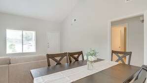 En matplats med ett träbord, en beige soffa och en vas med blommor.