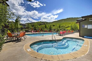 Un espace piscine doté de chaises longues et d’un jacuzzi, le tout entouré d’un paysage montagneux.