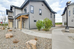 Une maison moderne à deux étages, dotée d’une façade en pierre, d’un porche et d’une allée aménagée avec des rochers et des arbustes.