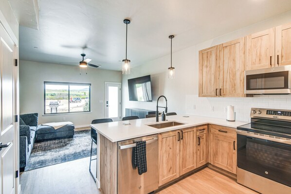 Une cuisine moderne avec des meubles en bois, un four en acier inoxydable et des luminaires suspendus.