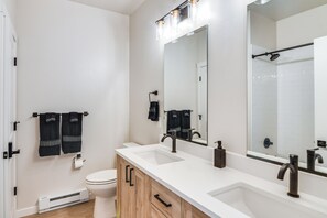 Une salle de bain moderne avec un meuble-lavabo blanc, deux vasques, un grand miroir et un espace douche.