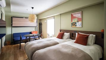 Una habitación de hotel con cama, escritorio, silla, lámpara colgante y un cuadro en la pared.