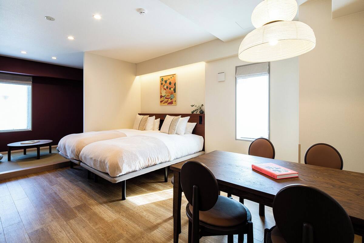 Una habitación de hotel con una cama grande, una mesa de comedor con sillas y un cuadro en la pared.