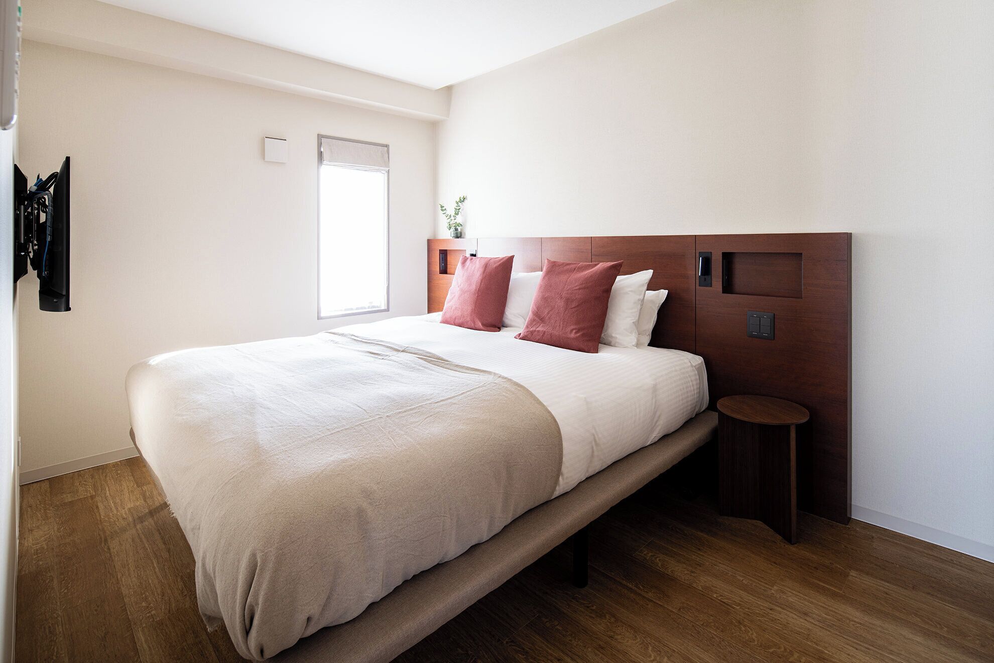 A modern bedroom with a large bed, a bedside table, and a window.