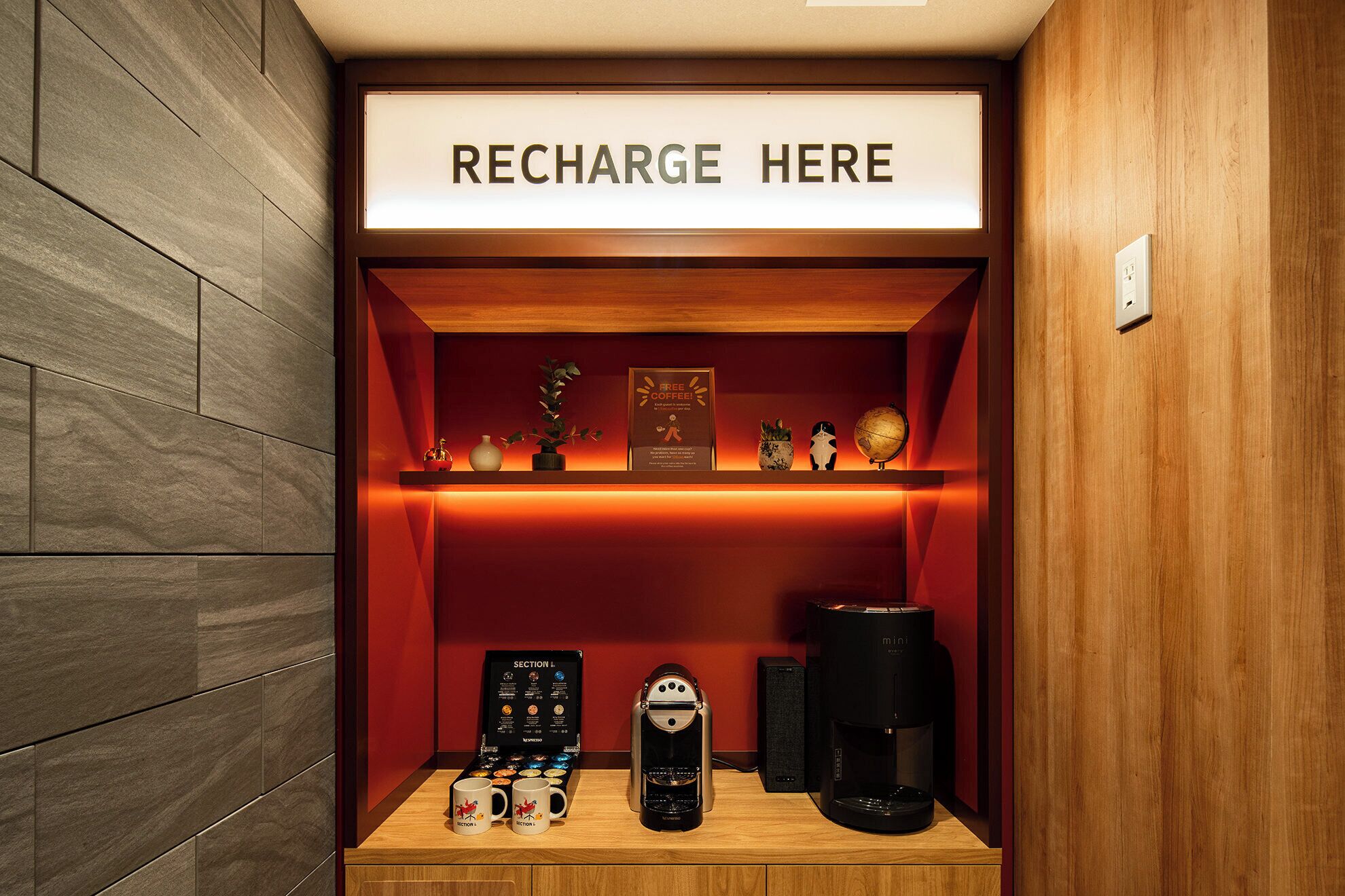 Een oplaadstation met een bord, een koffieapparaat en een selectie koffiekapsules.