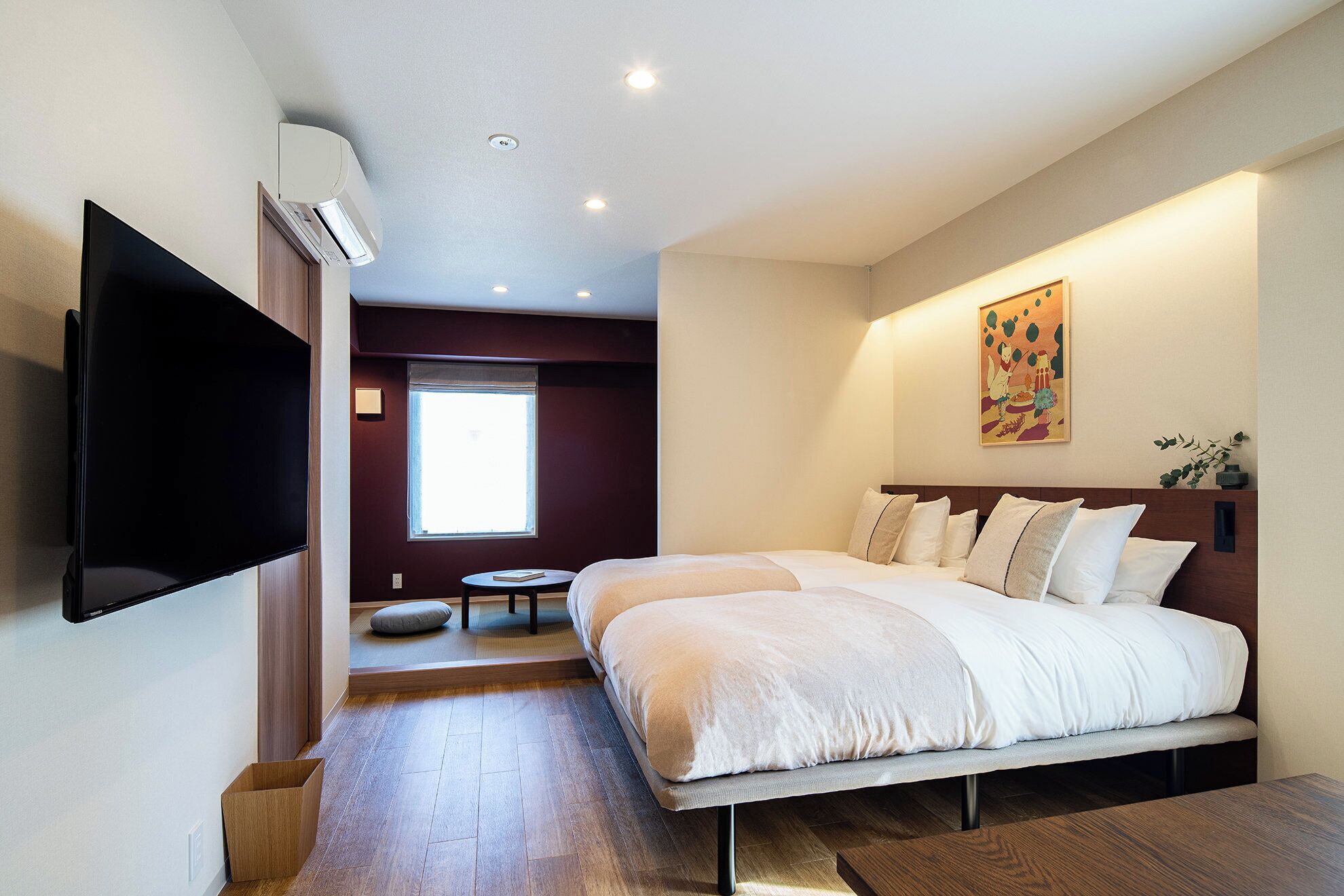A modern hotel room with a large bed, a flat-screen TV, and a window providing natural light.