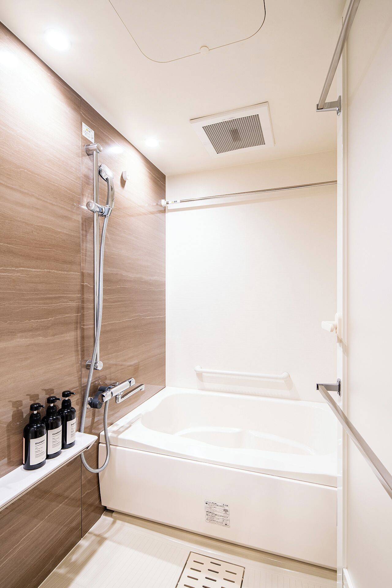 A modern bathroom with a bathtub, shower, and a shelf with toiletries.