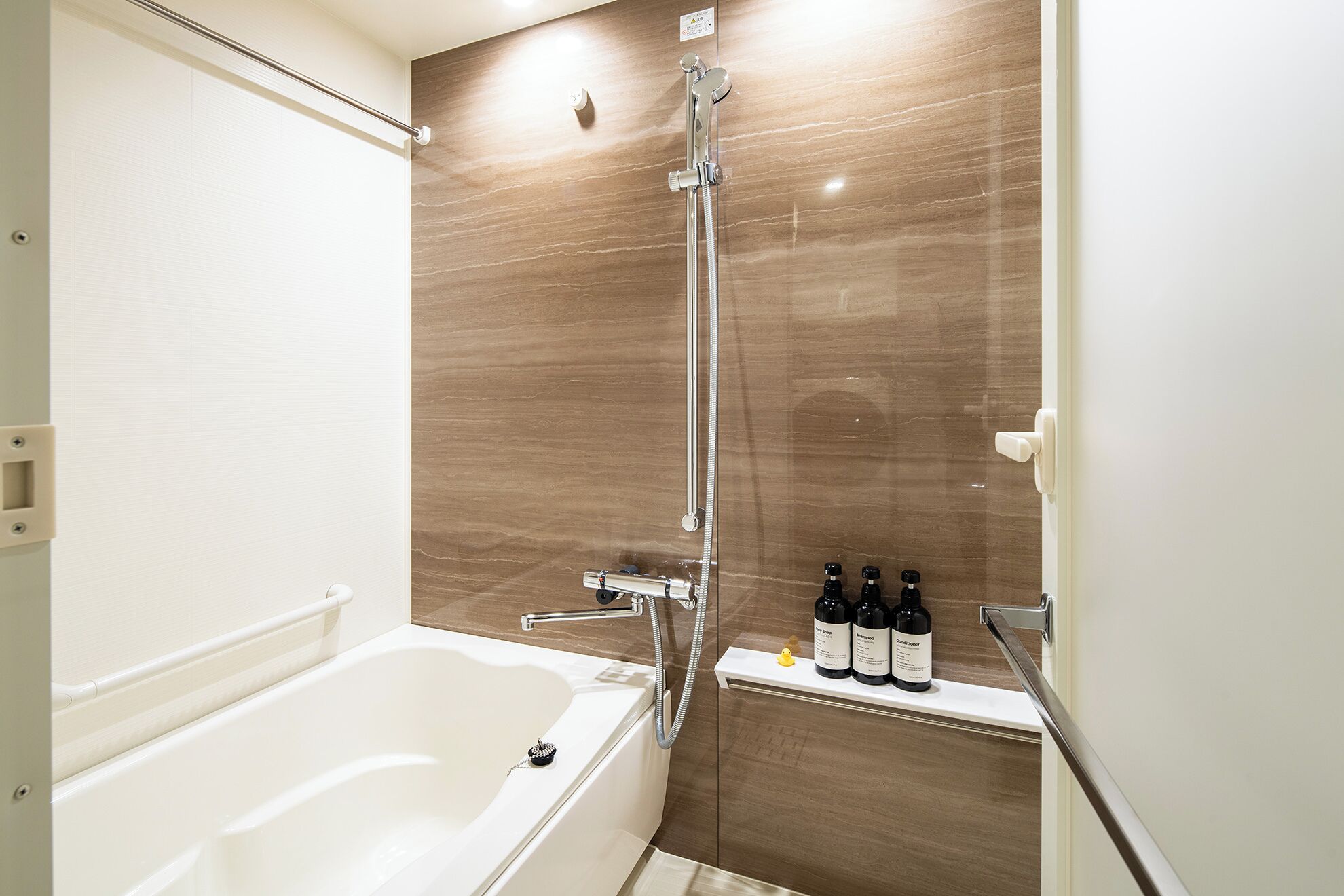 A modern bathroom with a bathtub, a shower with a rain showerhead, and a shelf with toiletries.