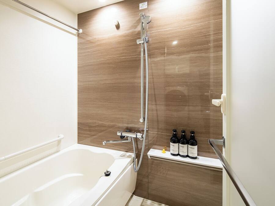 A modern bathroom with a bathtub, a shower with a rain showerhead, and a shelf with toiletries.