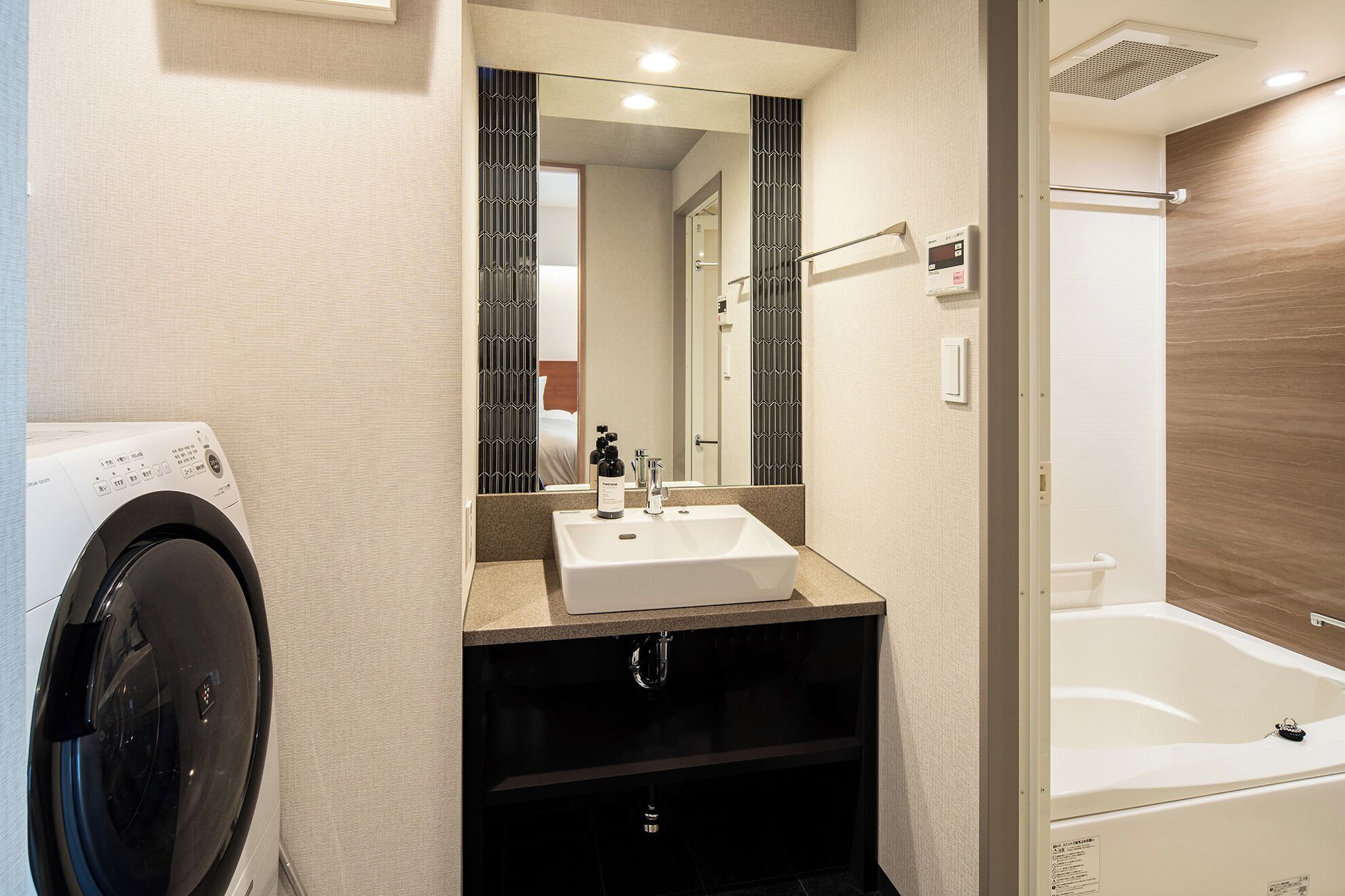 Une salle de bain moderne équipée d’un lave-linge intégré, d’un lavabo et d’une baignoire.