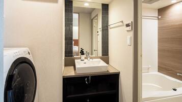 Une salle de bain moderne équipée d’un lave-linge intégré, d’un lavabo et d’une baignoire.