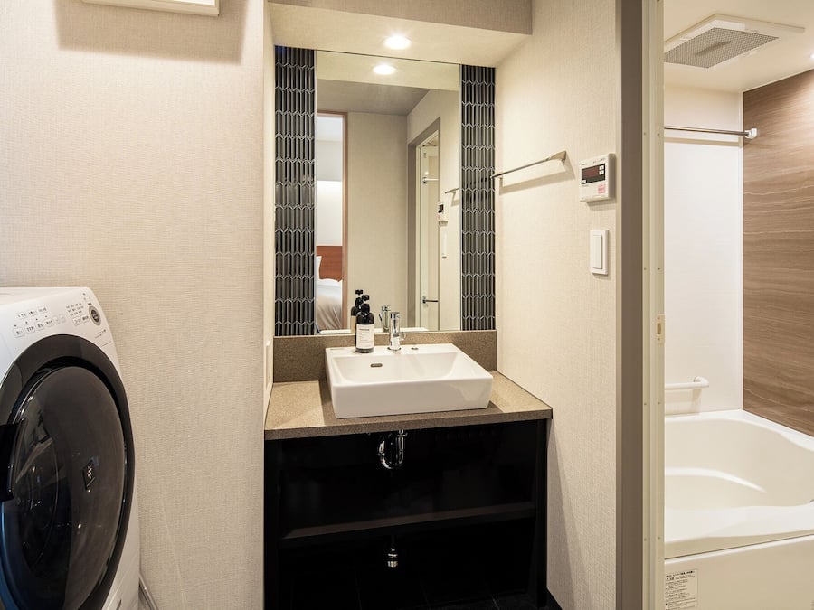 Une salle de bain moderne équipée d’un lave-linge intégré, d’un lavabo et d’une baignoire.