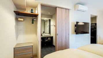 Ein modernes Hotelzimmer mit Bett, Fernseher, flachbildschirm-Fernseher an der Wand, Holzschrank, kleiner Nachttisch und Spiegel.