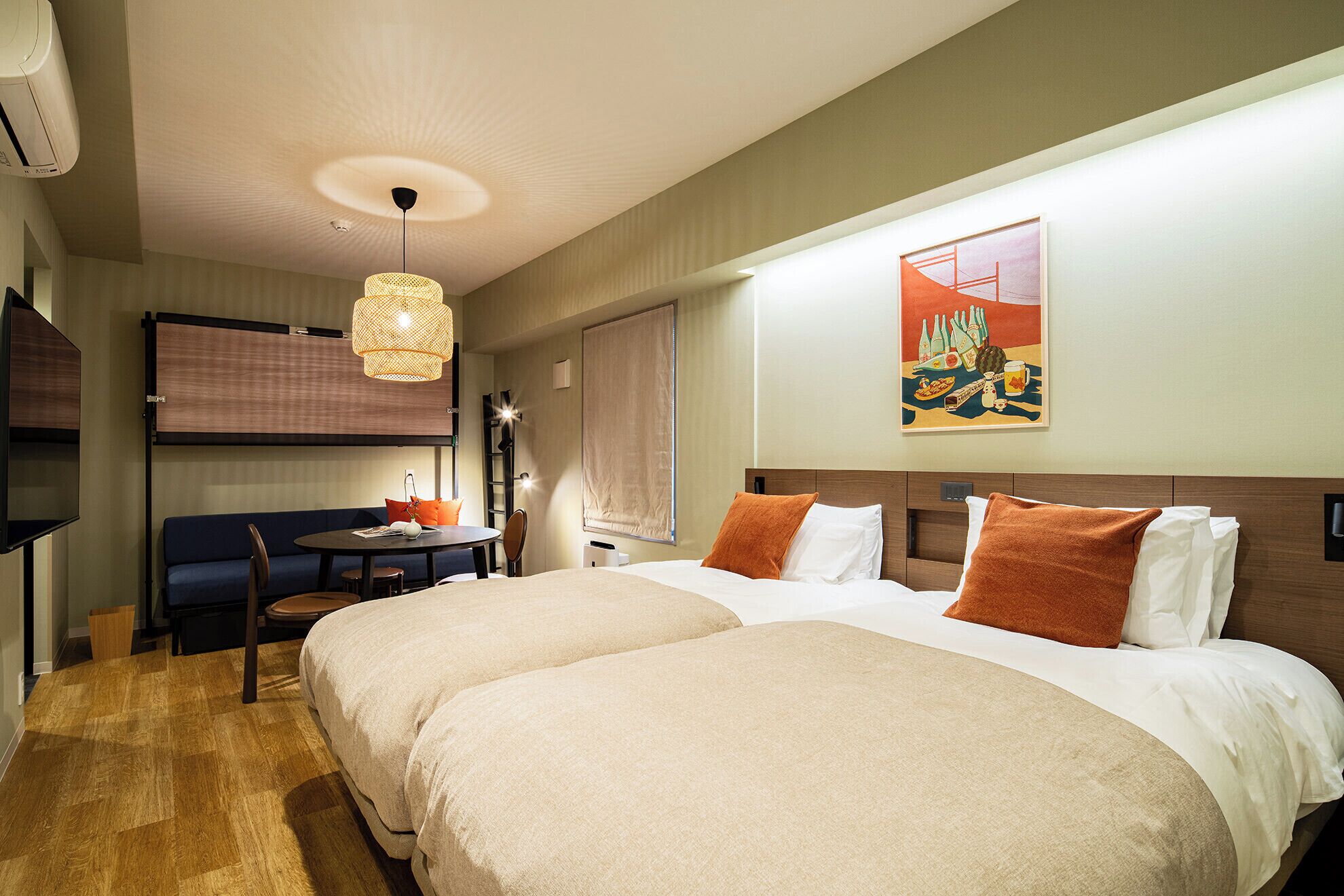 A hotel room with two beds, a dining table, a TV, and a painting on the wall.