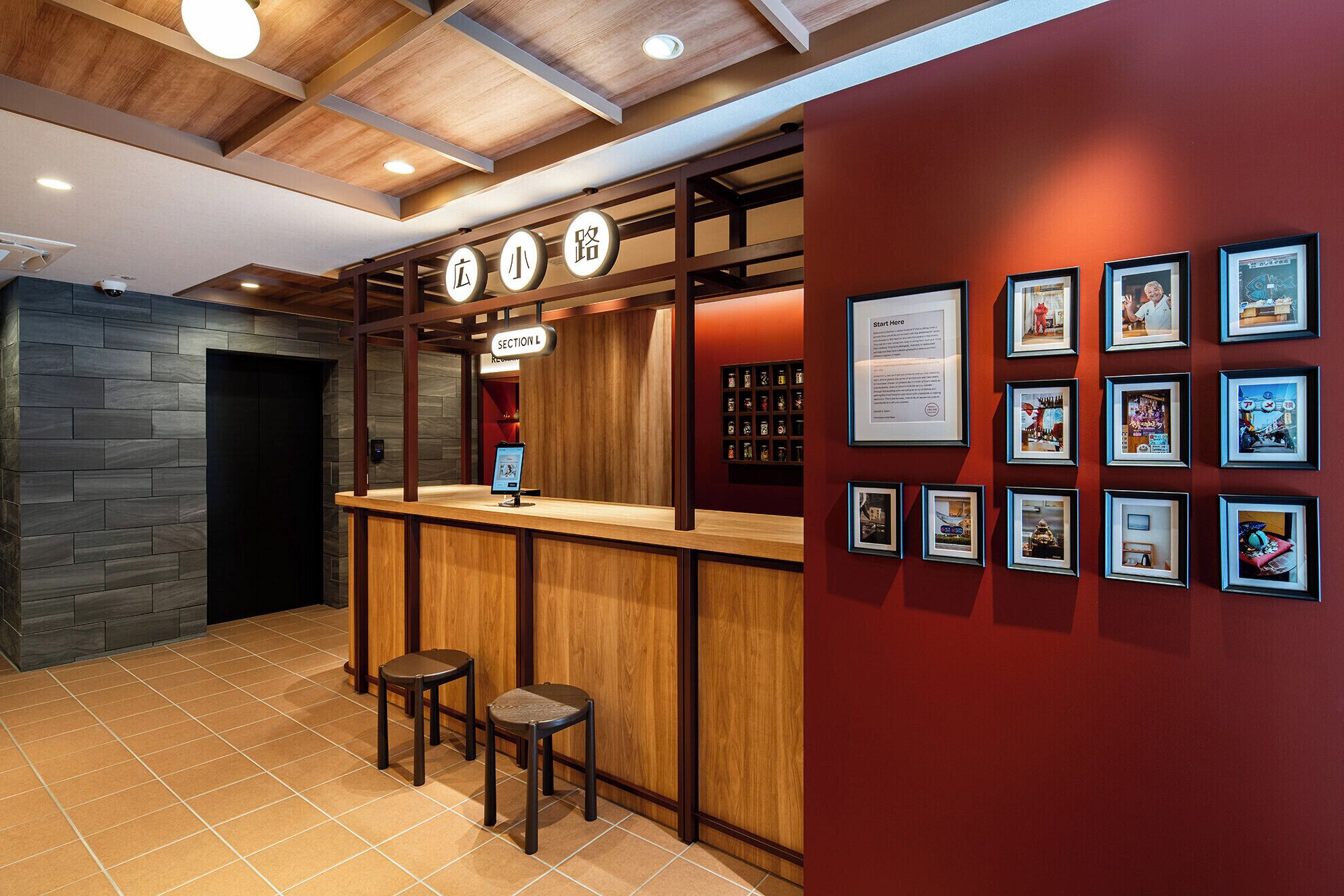 A bar area with a wooden counter, stools, and framed pictures on the wall.