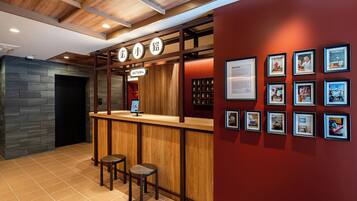 A bar area with a wooden counter, stools, and framed pictures on the wall.