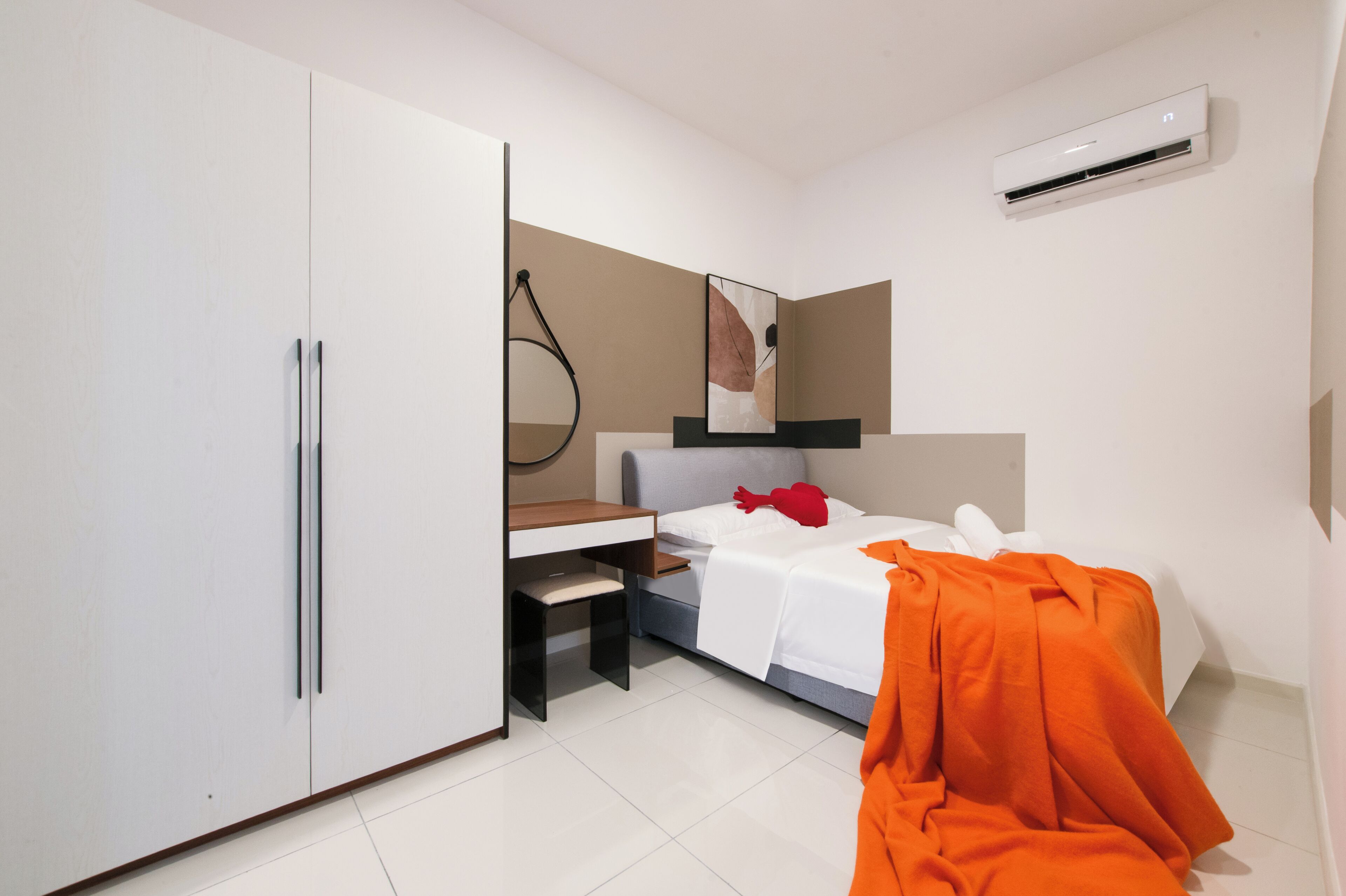 A modern bedroom with a bed, a desk, and a wardrobe.