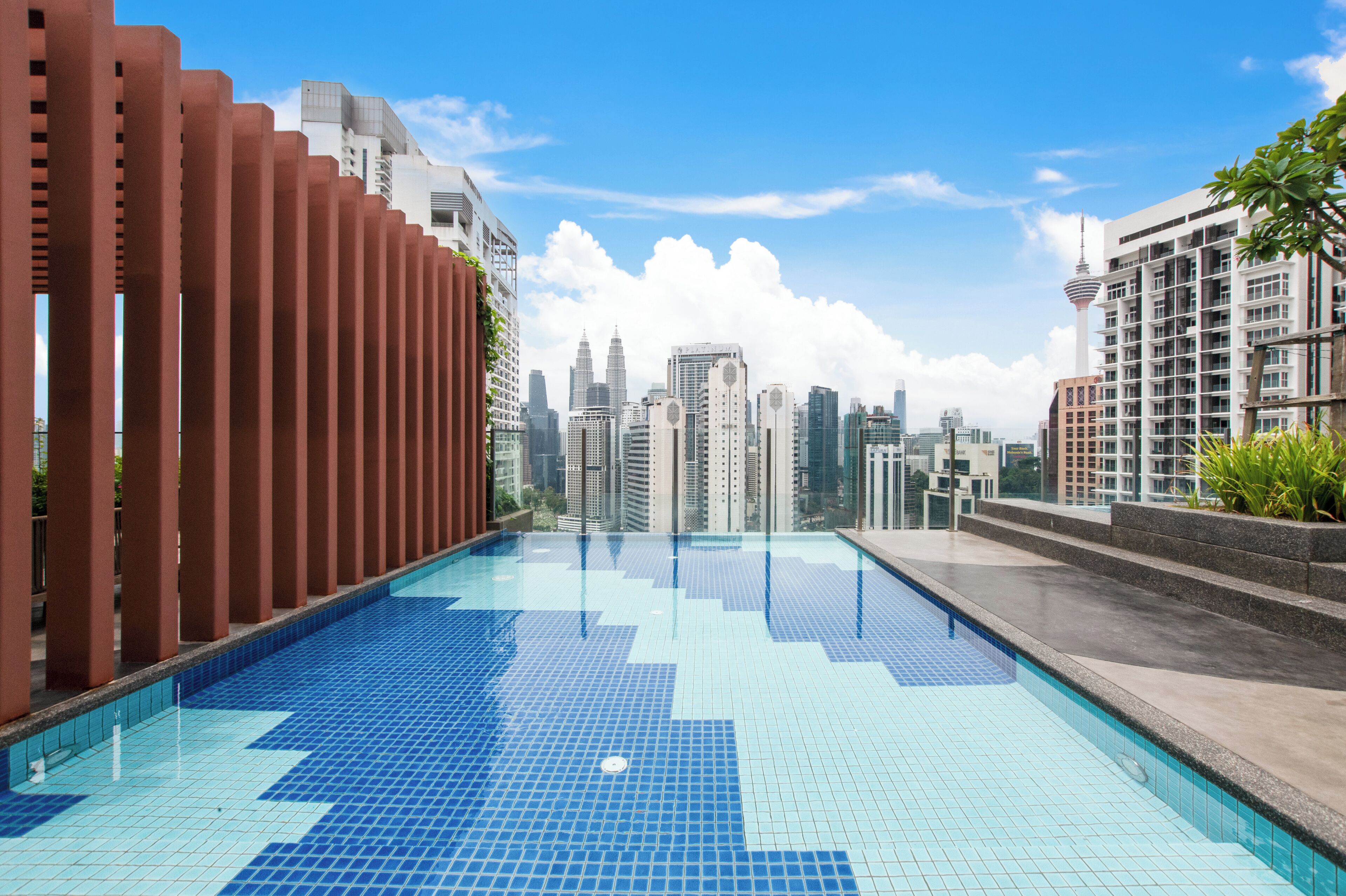 Una piscina en la azotea con vistas a un horizonte urbano, con edificios modernos y una torre distintiva.