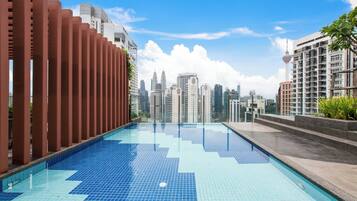 Una piscina en la azotea con vistas a un horizonte urbano, con edificios modernos y una torre distintiva.