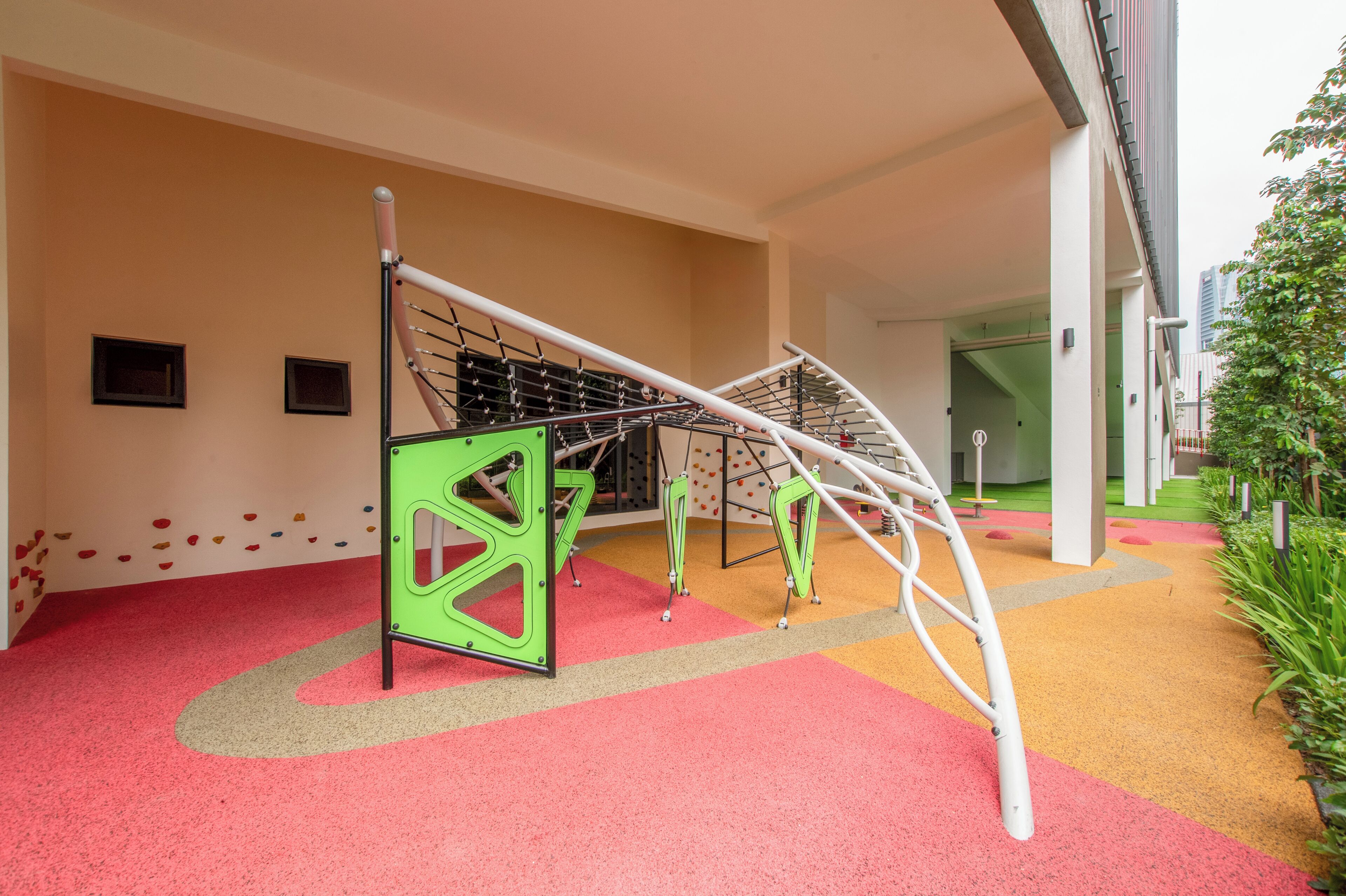 Un área de juegos infantiles con estructuras para escalar y suelo colorido.