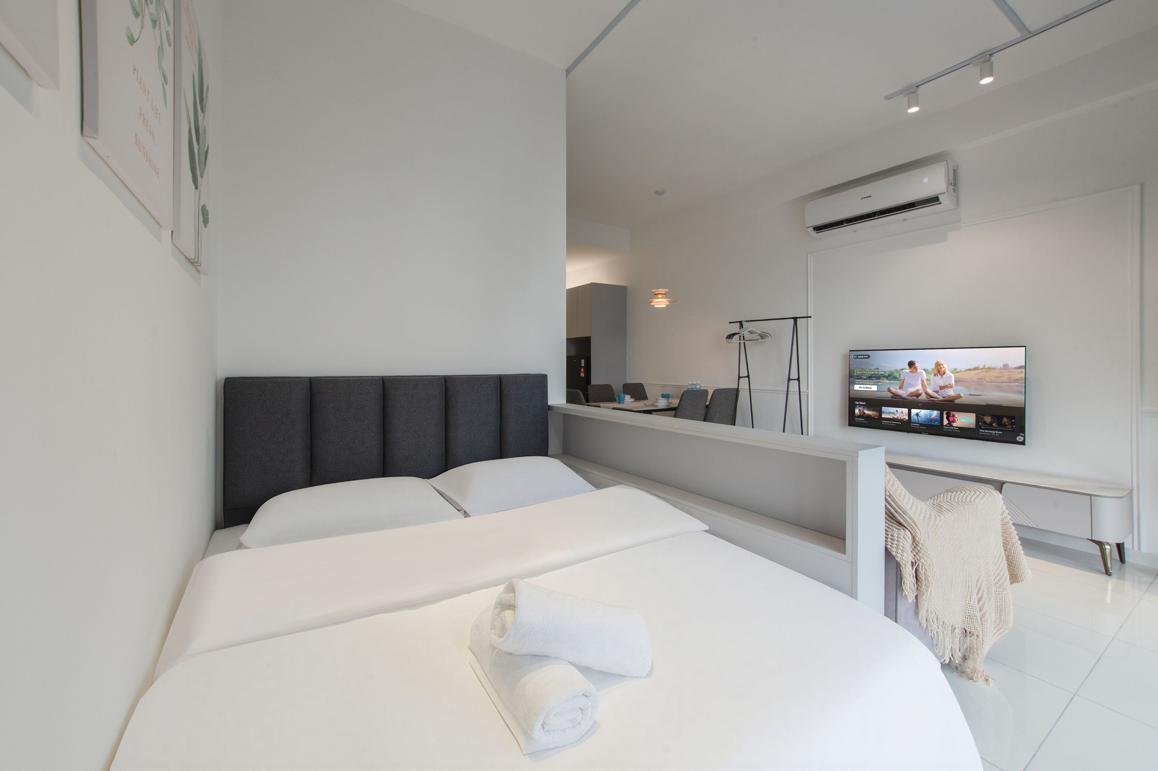 A modern hotel room with a large bed, a flat-screen TV mounted on the wall, and a small desk area.