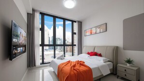 A modern hotel room with a large bed, a bedside table, a TV mounted on the wall, and a window with a city view. - Majestic by Avery &10 mins to Twin Tower (Kuala Lumpur)