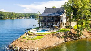 A lakeside house with a pool, a deck, and a stone wall. - Luxe Lake Martin Home  Pool Hot Tub  Boat Dock (Dadeville)