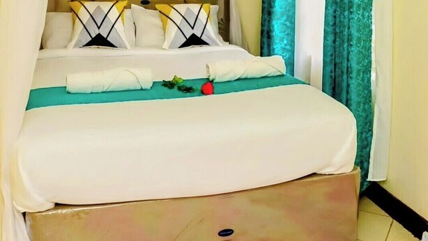 A bed with a canopy, a headboard, and pillows. - Machakos inn hotel  (Machakos)