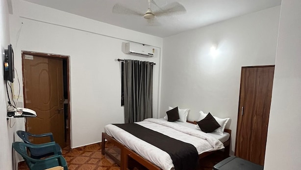 A small, clean room with a bed, a desk, a chair, and a wardrobe. - Hotel Sai Deep Place (Baga)