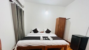 A hotel room with a bed, a wardrobe, a small black refrigerator, and a patterned floor. - Hotel Sai Deep Place (Baga)