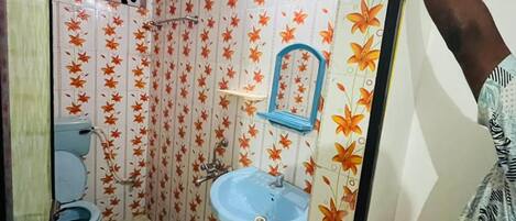 A small bathroom with a toilet, sink, and mirror. The walls are decorated with a floral pattern.
