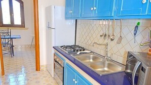 A kitchen with blue cabinets, a stove, sink, and a refrigerator.