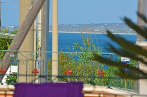 En balkon med udsigt over havet og en fjern kystlinje.