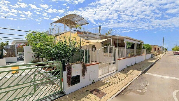 A residential building with a covered patio, a gated entrance, and a clear sky. - Casa Nima: A welcoming independent house situated at a short distance from the beach, with Free WI-FI. (Patù)