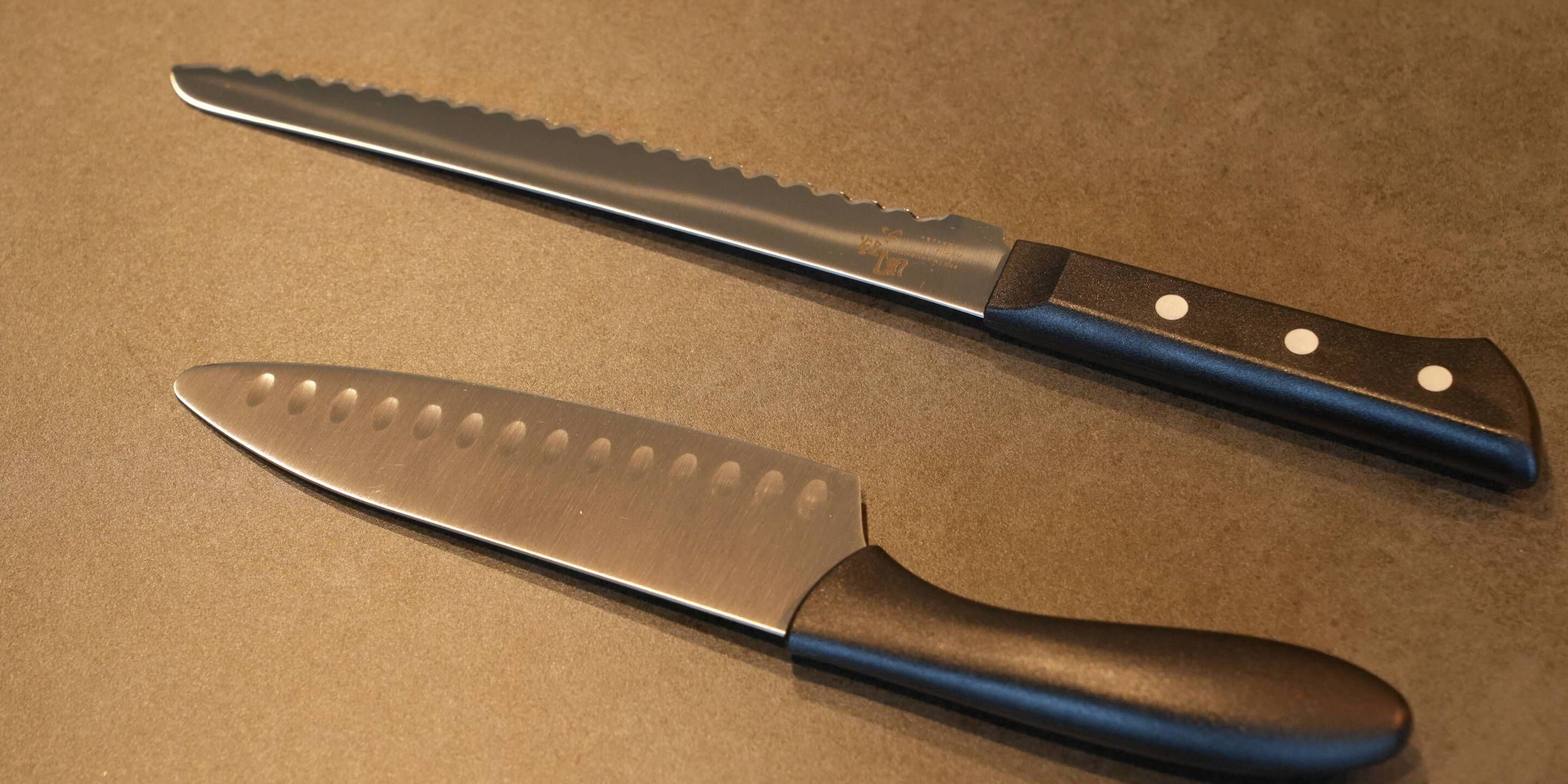 Two kitchen knives with blue handles on a brown countertop.